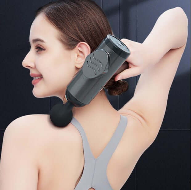 Woman using a massage gun muscle relaxation instrument on her shoulder for relief.